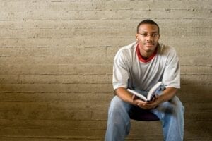 Young man sitting on bench with book